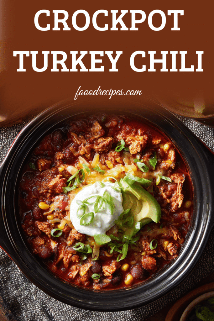 Overhead shot of crockpot turkey chili with beans, corn, avocado, sour cream, and scallions in a black bowl